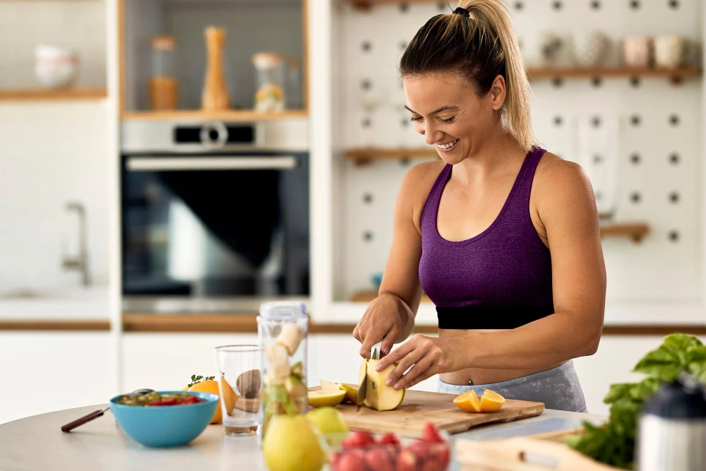 Mulher sorrindo preparando várias superfoods em bancada de cozinha