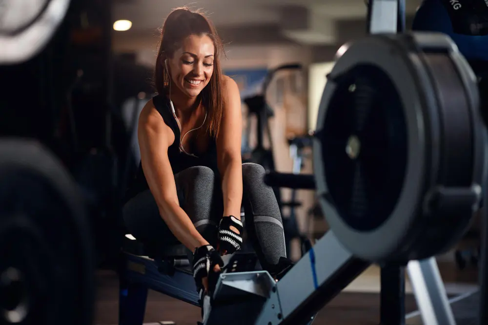 Mulher com roupas esportivas sentada ajustando  equipamento de academia 