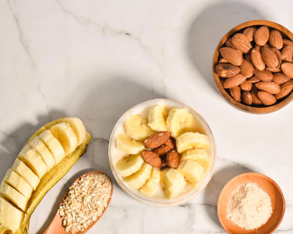 Alimentos ricos em l-triptofano vistos de cima, como banana, aveia, e castanhas.